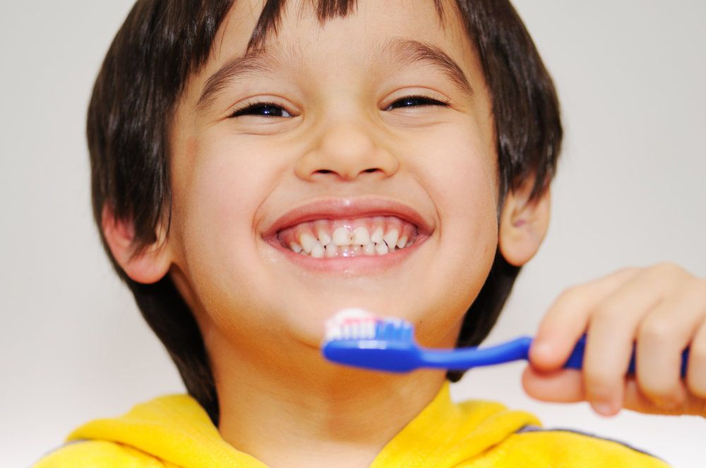 Child smiling holding toothbrush.
