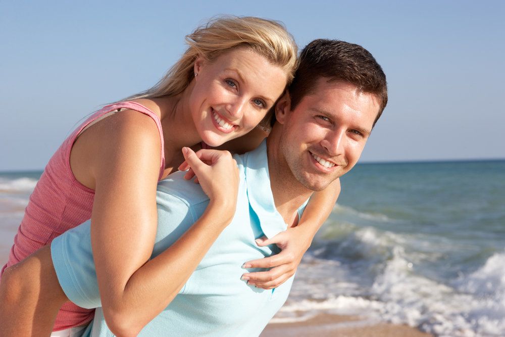 A happy couple, with beautiful smiles, hanging out at the beach